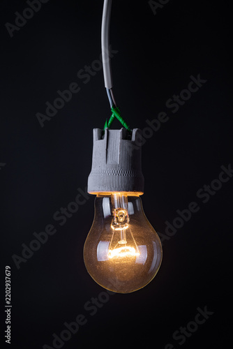 Glowing vintage light bulb close up on black background