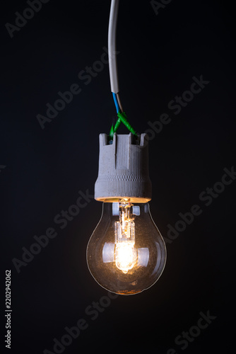 Glowing vintage light bulb close up on black background