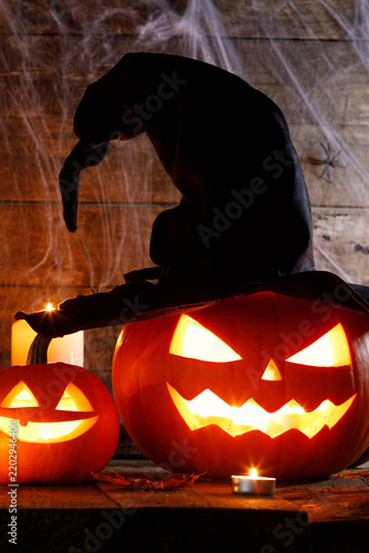 Halloween pumpkins with a witch hat and glowing candles on a wooden background