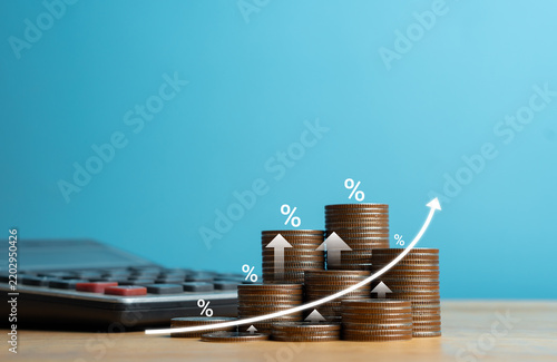 Increasing coin stacks with percentage icons and upward growth arrow for interest rate rise, inflation, and financial profit concept on blue background