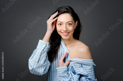 Portrait of a smiling young woman in a striped shirt with an open shoulder