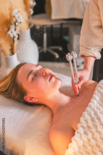 Woman receiving tuning fork sound therapy during a holistic wellness session, representing neurowellness, nervous system regulation, sensory relaxation and restorative self care.