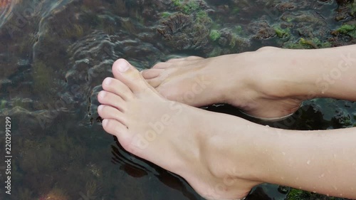 little girl holding bare feet on the seashore
