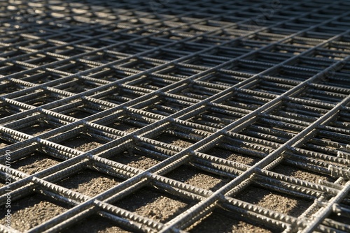 Galvanised steel mesh with a welded wire grid and metallic spangle texture, shown in hard raking light for an industrial background and overlay