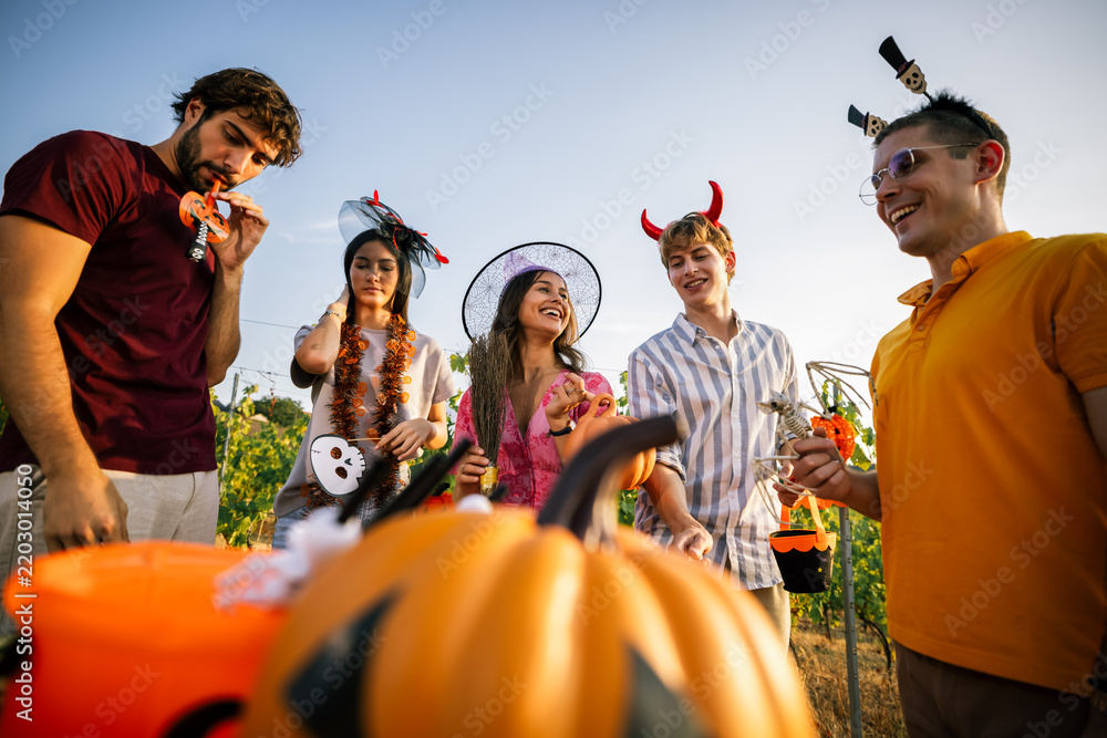 Obraz premium Low angle view of young people wearing Halloween accessories having fun at an outdoor event.