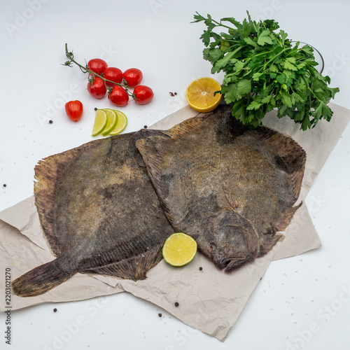 Fotografía Raw flounder turbot fish on parchment paper with cherry tomatoes lemon and fresh