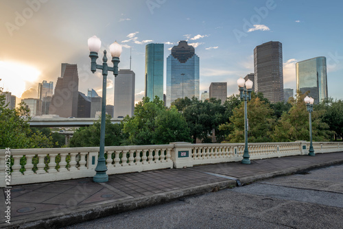 Sabine Street Bridge in Houston, Texas, features vintage-style lamp posts and a decorative railing. The foreground shows the patterned sidewalk and street. 