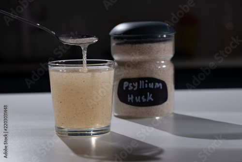 Soaked psyllium husk gel drips from a spoon into a glass on a kitchen counter