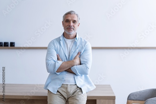 Smiling middle aged business man, confident mid adult professional businessman executive standing in office