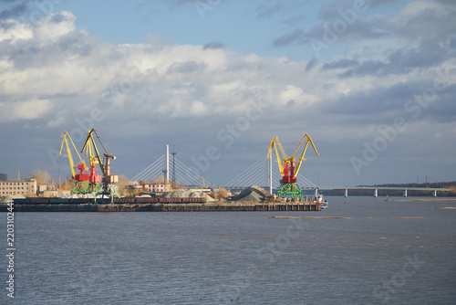 Cranes at a cargo port against the backdrop of the sky and river