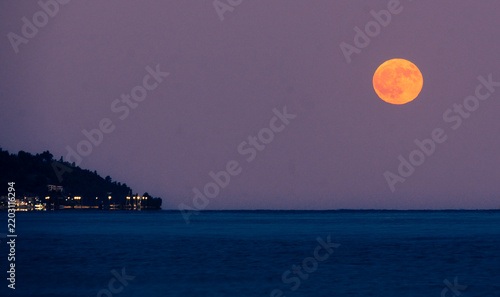 Warm moon glows over calm Aegean sea in Greece