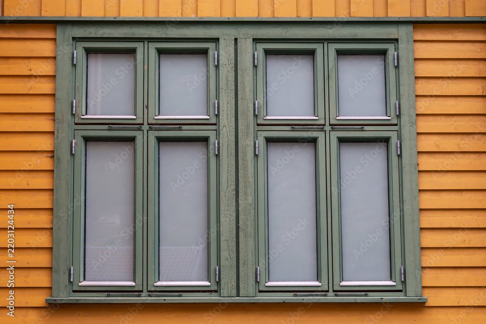 Fototapeta premium Double window with green frames in yellow wooden building wall