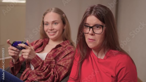 Women play games. Relaxed friends enjoying video games with cheerful interactions. Two women engage in friendly game night amid comfortable surroundings and joyful laughter