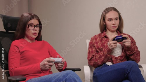 Women play games. Relaxed friends enjoying video games with cheerful interactions. Two women engage in friendly game night amid comfortable surroundings and joyful laughter