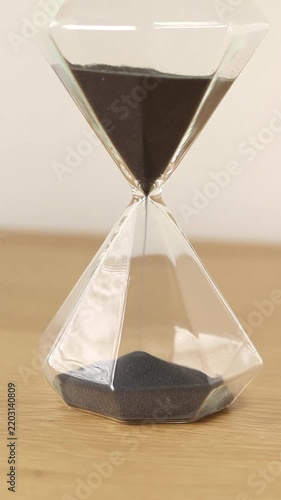 Hourglass on a wooden table with white background. Vertical video. Time running concept.