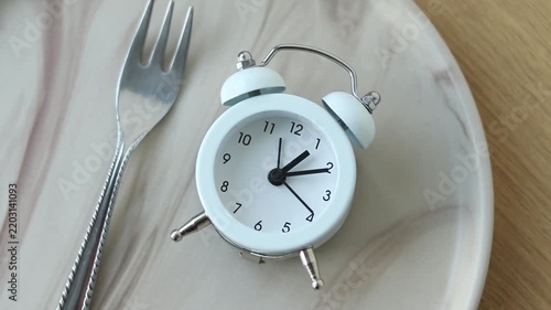 Alarm clock and fork on and empty plate. Intermittent fasting concept.