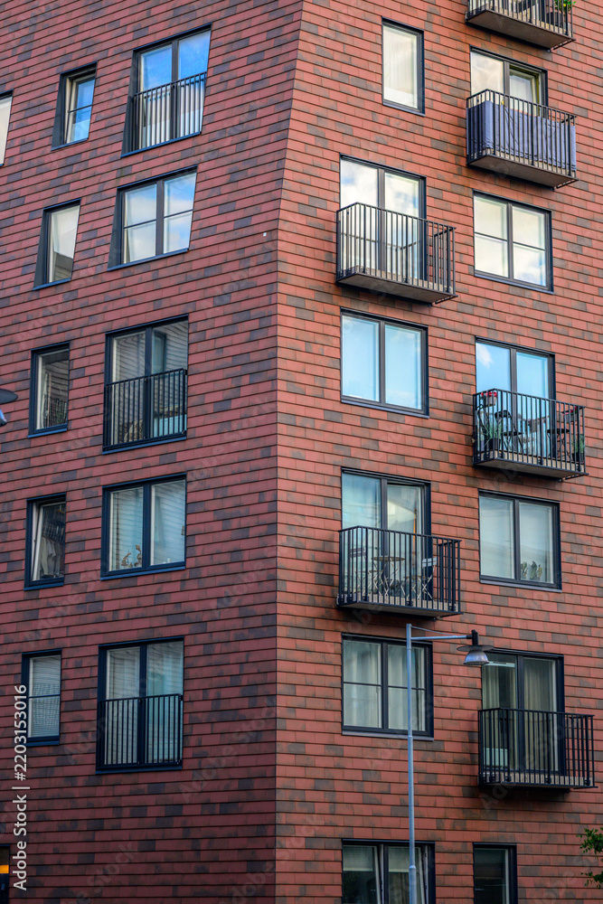 Obraz premium Modern brick apartment tower with balconies and dark windows.