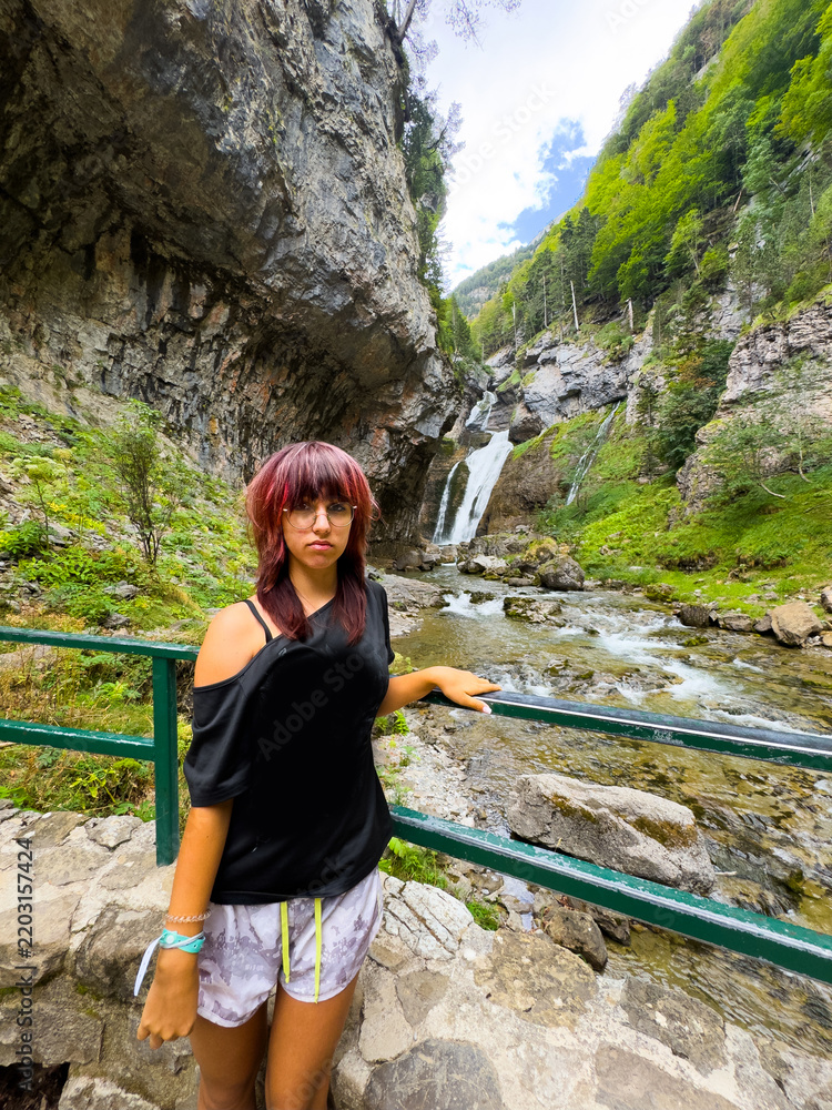 Fototapeta premium a girl t looks at a waterfall, happy young traveling