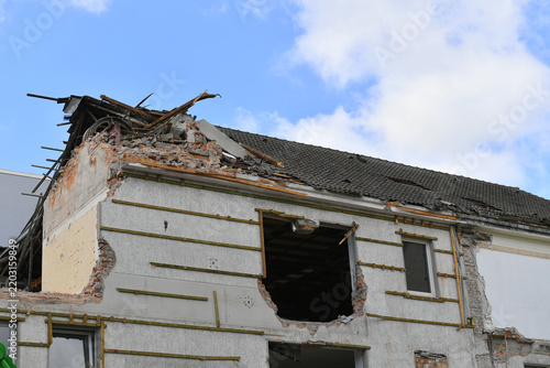 Demolition site showing a partially torn down apartment building wall and exposed structure.