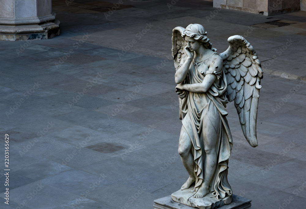 Obraz premium Grief and mourning concept, stone angel statue with wings standing in a pensive pose in a quiet courtyard for funeral or memorial service themes