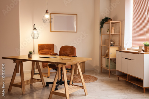 Interior of light office with workplace, shelf unit and glowing lamps