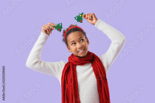 Teenage African-American girl in hoop with Christmas trees on lilac background