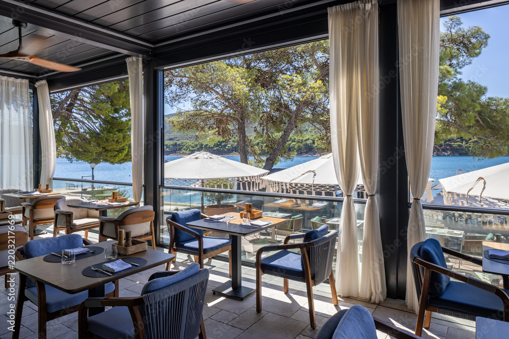 Obraz premium Elegant restaurant terrace with sea view dining tables and curtain decorations