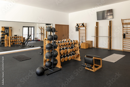 Modern luxury gym interior with wooden dumbbells and fitness equipment