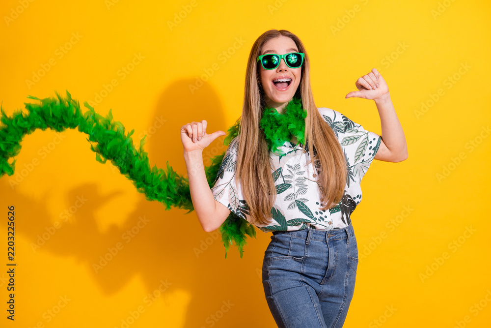 Obraz premium Cheerful young woman in tropical printed shirt with green boa posing against vibrant yellow background