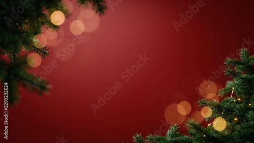 Christmas background with green pine branches and golden bokeh lights on a deep red backdrop, perfect for holiday greeting cards and festive designs