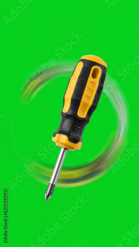 A stubby screwdriver with a black and yellow handle slowly rotating in a 360-degree loop against a bright green screen background