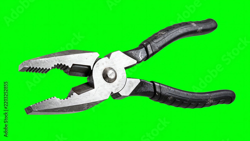 Heavy duty steel combination pliers rotating and opening jaws against a bright green screen background for chroma keying