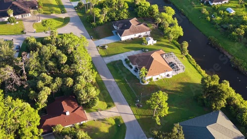 Flood water canal in North Port residential community with private homes, green yards and organized streets, capturing suburban sprawl, wealth, and housing market growth in the USA.