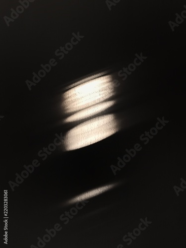 Abstract image of a shaft of sunlight from a window creating a pattern on a dark wooden surface.