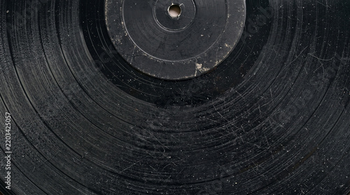 Close up of a vintage black vinyl record with visible dust and surface scratches on the grooves