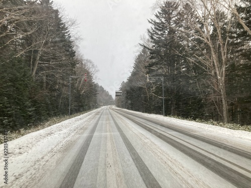 Snow-covered straight road through a winter forest in Hokkaido, Japan