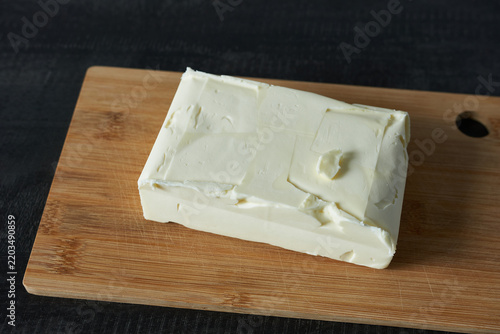 Butter on a wooden cutting board against a black background.