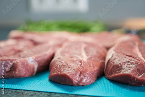 Raw beef chops on a cutting board with herbs, selective focus.