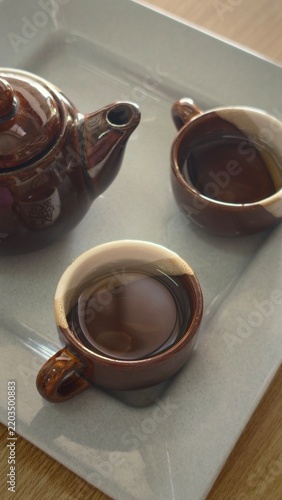 Cup of tea and teapot on wooden table, stock photo