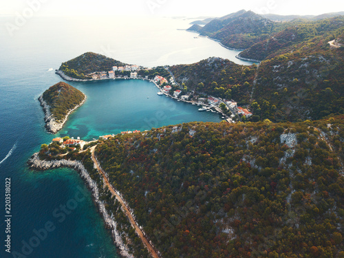 Aerial view of remote Croatian island harbour village nestled in sheltered bay between forested hills, Lastovo Adriatic Sea