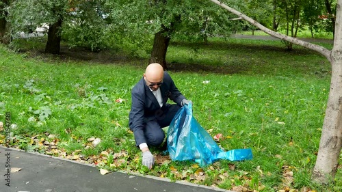 Businessman volunteer cleaning up litter in the city park