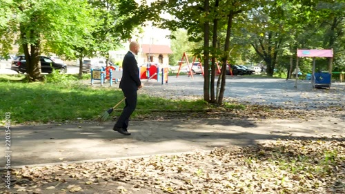 Funny businessman flying on a broomstick through a city park