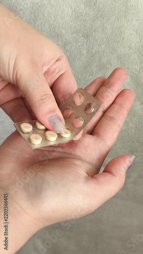 Hand pressing tablets out of a blister pack into the palm, illustrating medication use, taking pills, pain relief, treatment and home healthcare.