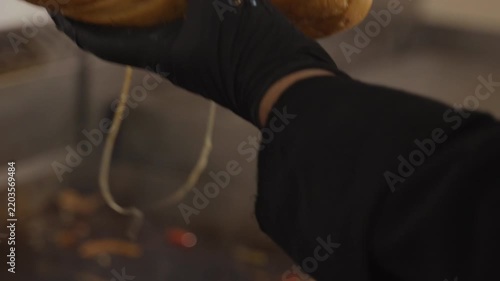Chef filling a long bread roll with hot chicken, grilled vegetables and melted cheese, preparing a loaded takeaway sandwich in a restaurant.