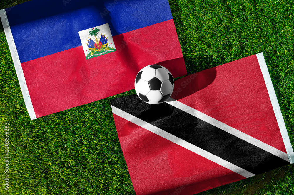 Obraz premium Haiti vs. Trinidad and Tobago football match. National flags on green grass with soccer ball in the middle. Football background for international match.