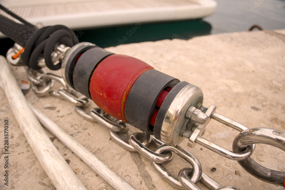 Obraz premium Close-up of a rubber mooring damper and steel chain on a dock in the harbor of Rijeka, Croatia. Marine yacht mooring system detail.