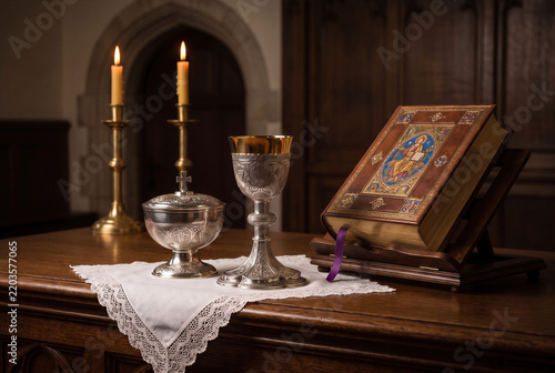 Holy communion chalice, eucharist ciborium and bible on church altar for sacred liturgy sacrament with candle.