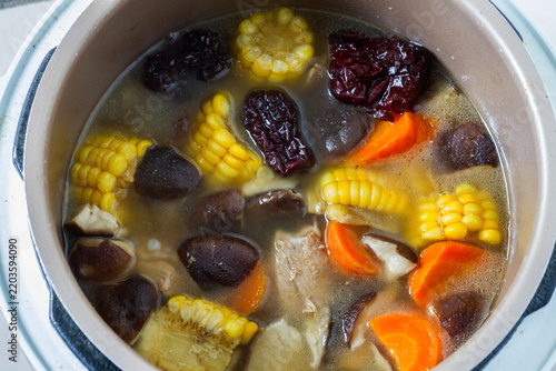 Фотография A pot of simmered nutritious soup with corn, jujube, mushroom and carrot in broth