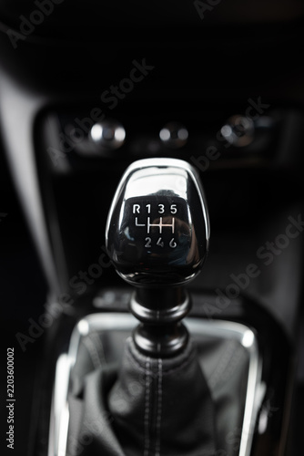 Six-speed manual gear shift knob with chrome trim and leather gaiter on center console inside modern vehicle
