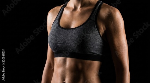 Athletic female torso with muscular abs and sweat wearing a sports bra.